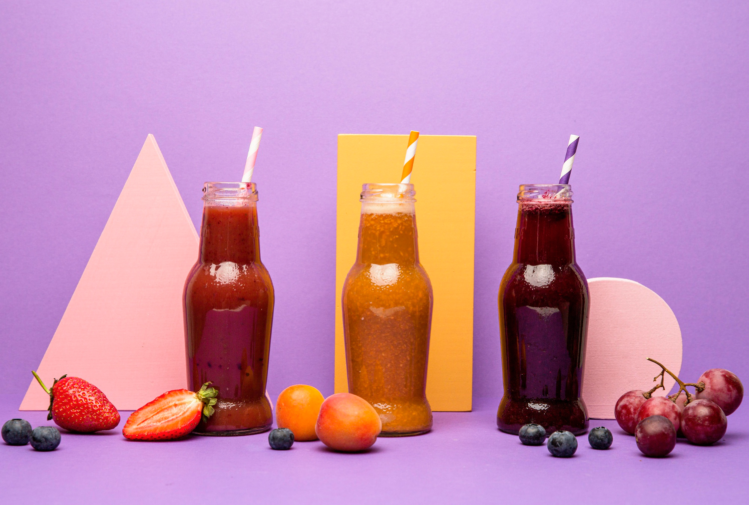 Cold pressed juices bottles on purple background