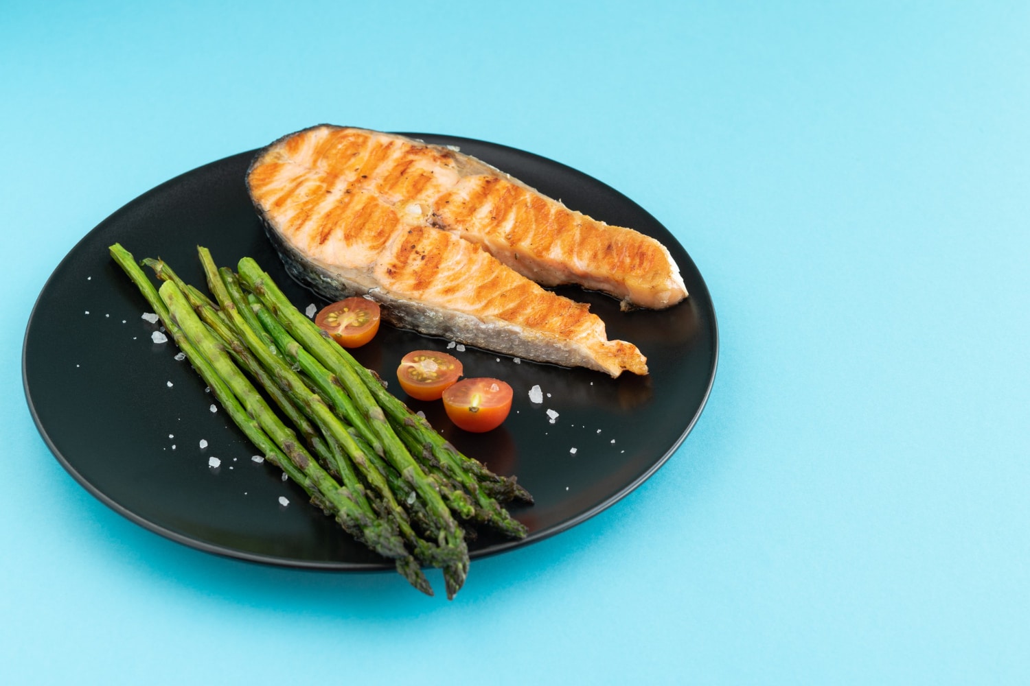 Pescatarian meal of grilled salmon with vegetables in blue background