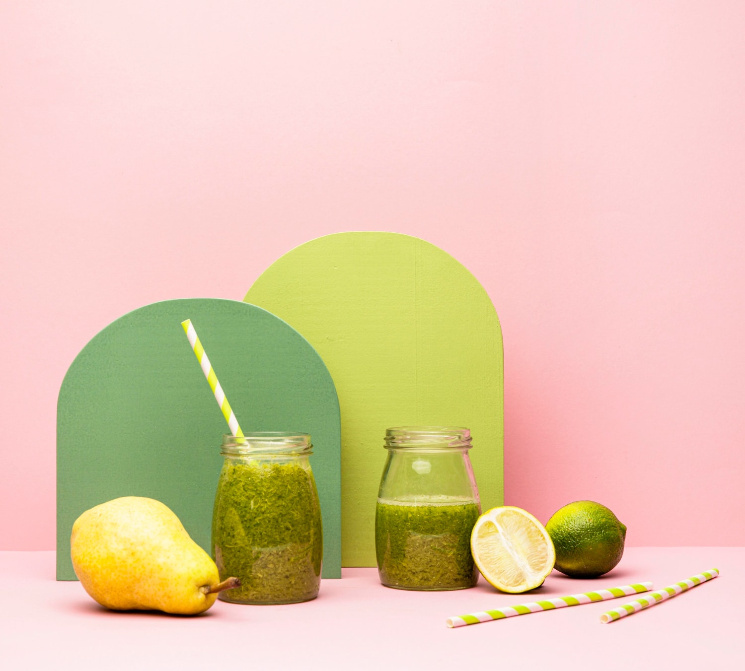 Green wellness shot juice bottle on pink background